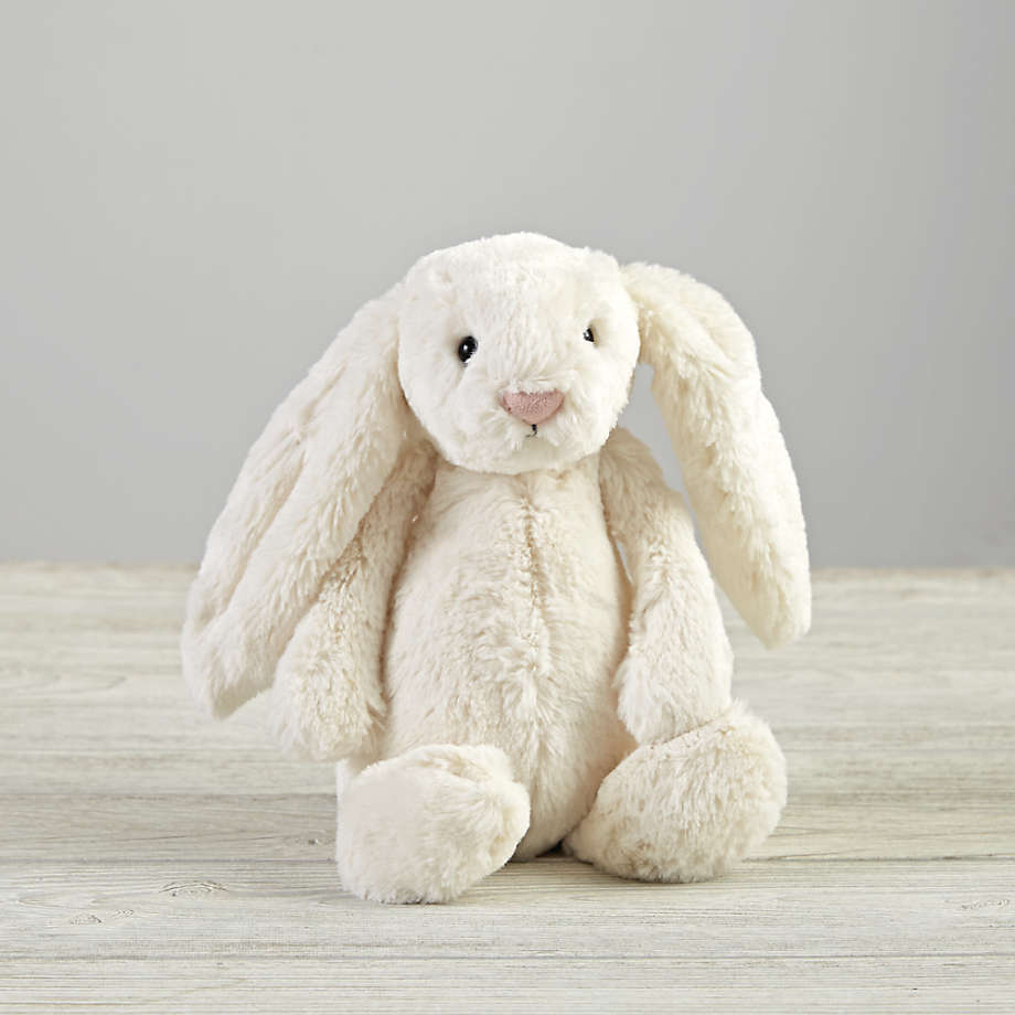 A soft white bunny sitting on the wooden floor