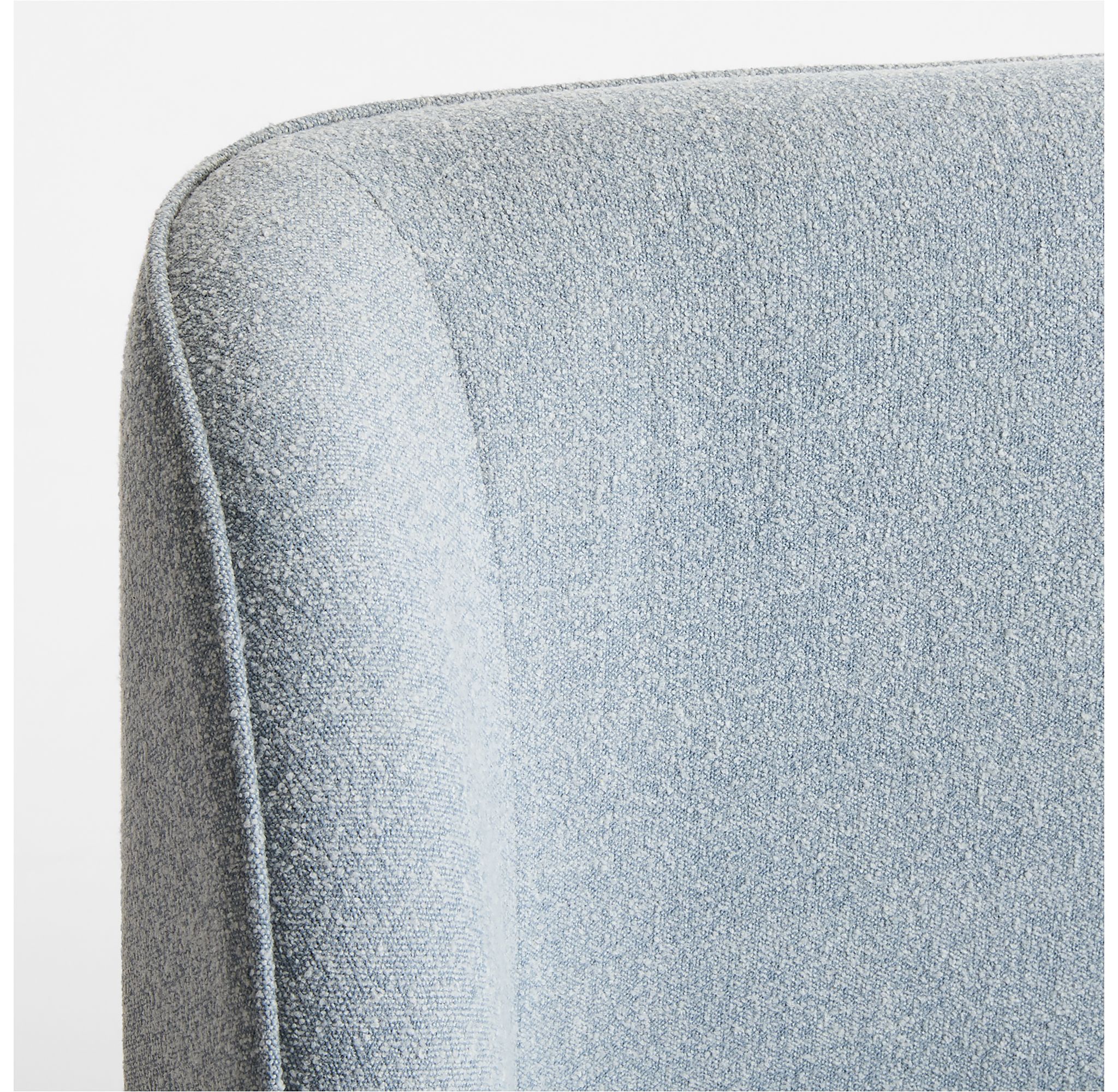 Close-up detail of the corner of a blue upholstered bed.
